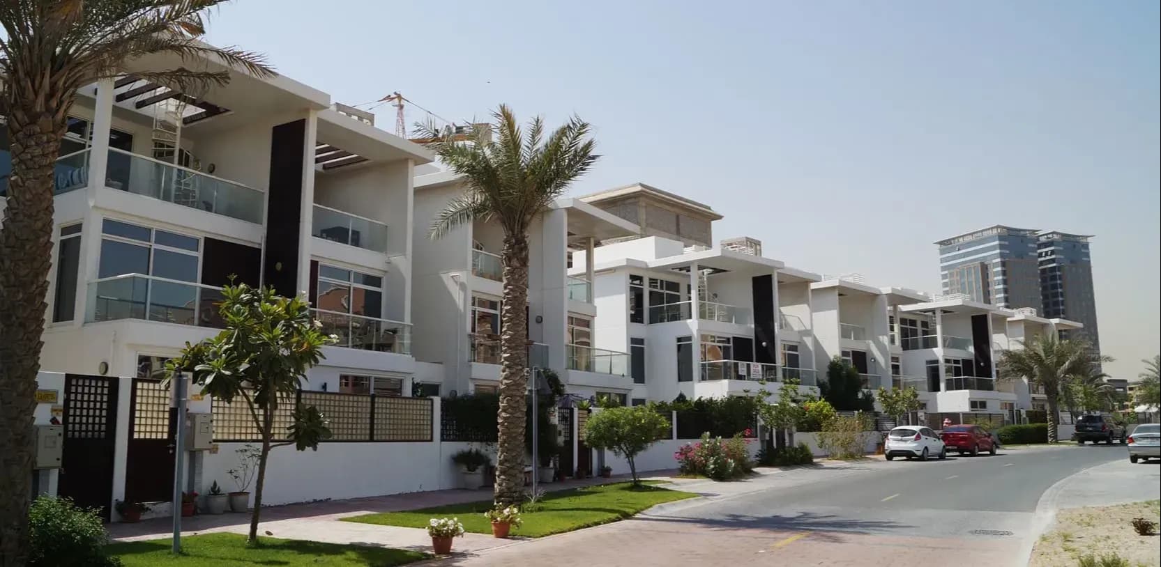 Street of modern white townhouses with palm trees in Al Hamra Village, Ras Al Khaimah, UAE.