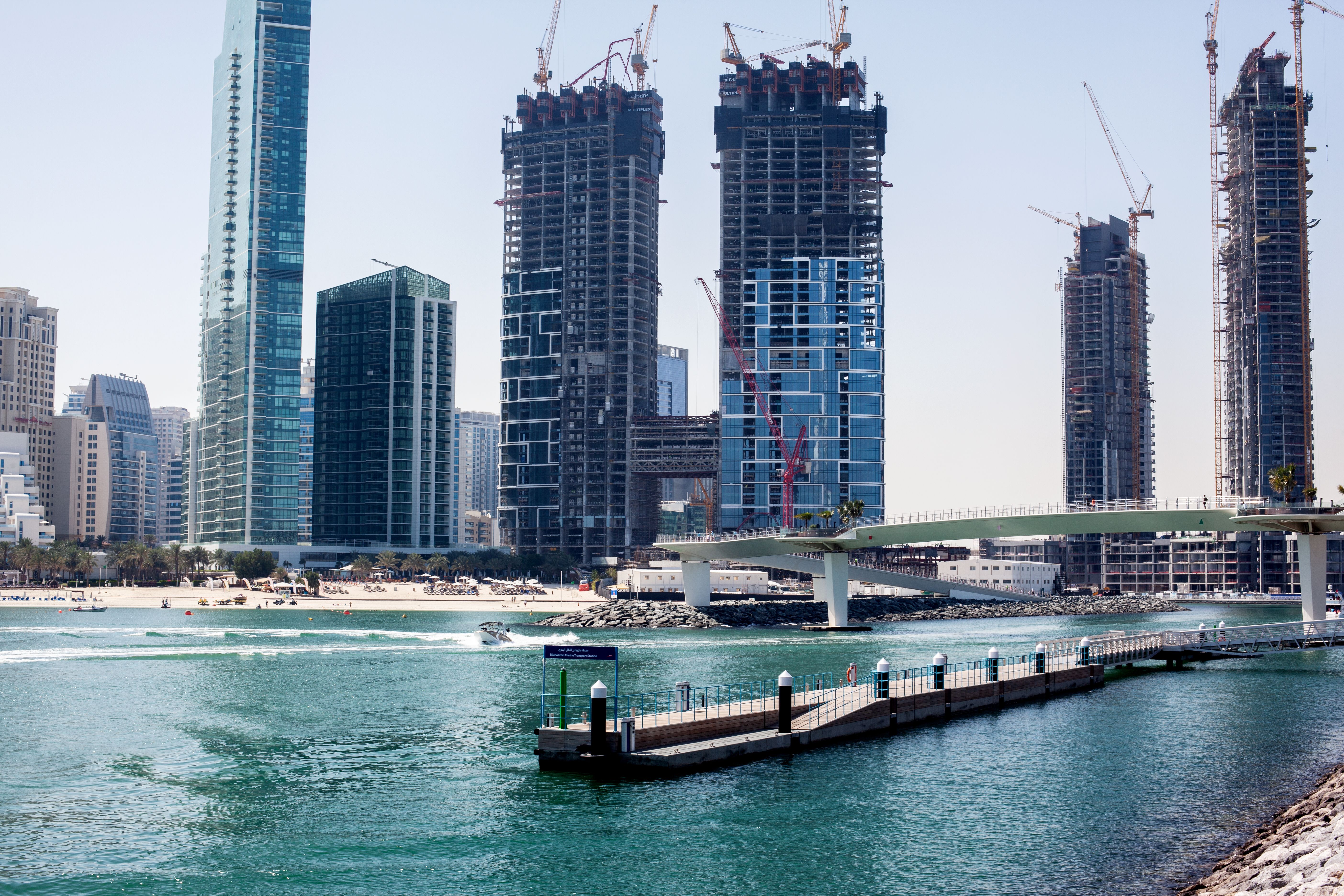 Residential towers under construction with cranes on the Dubai waterfront