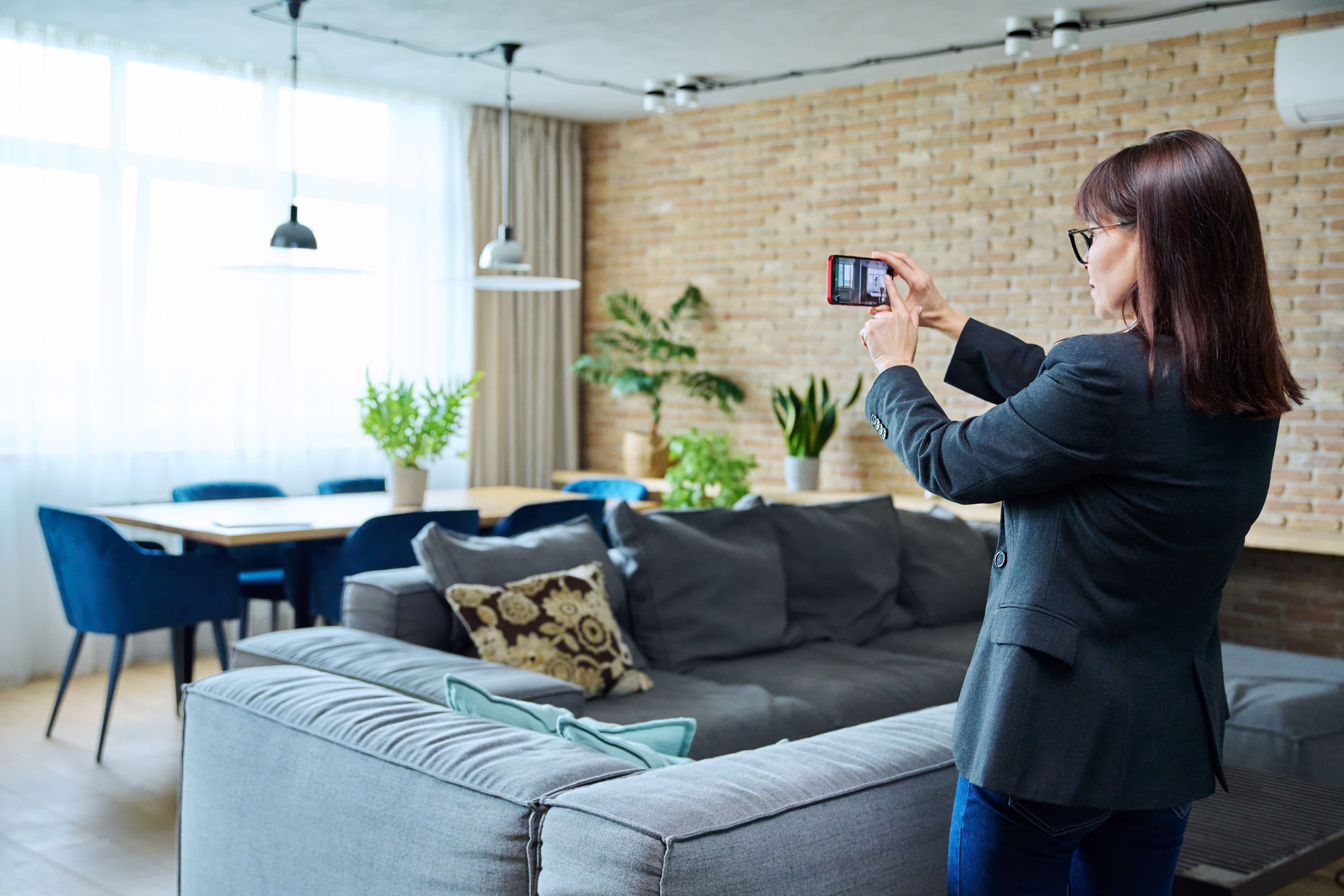 Real estate agent photographing a furnished Dubai apartment for a property valuation before selling