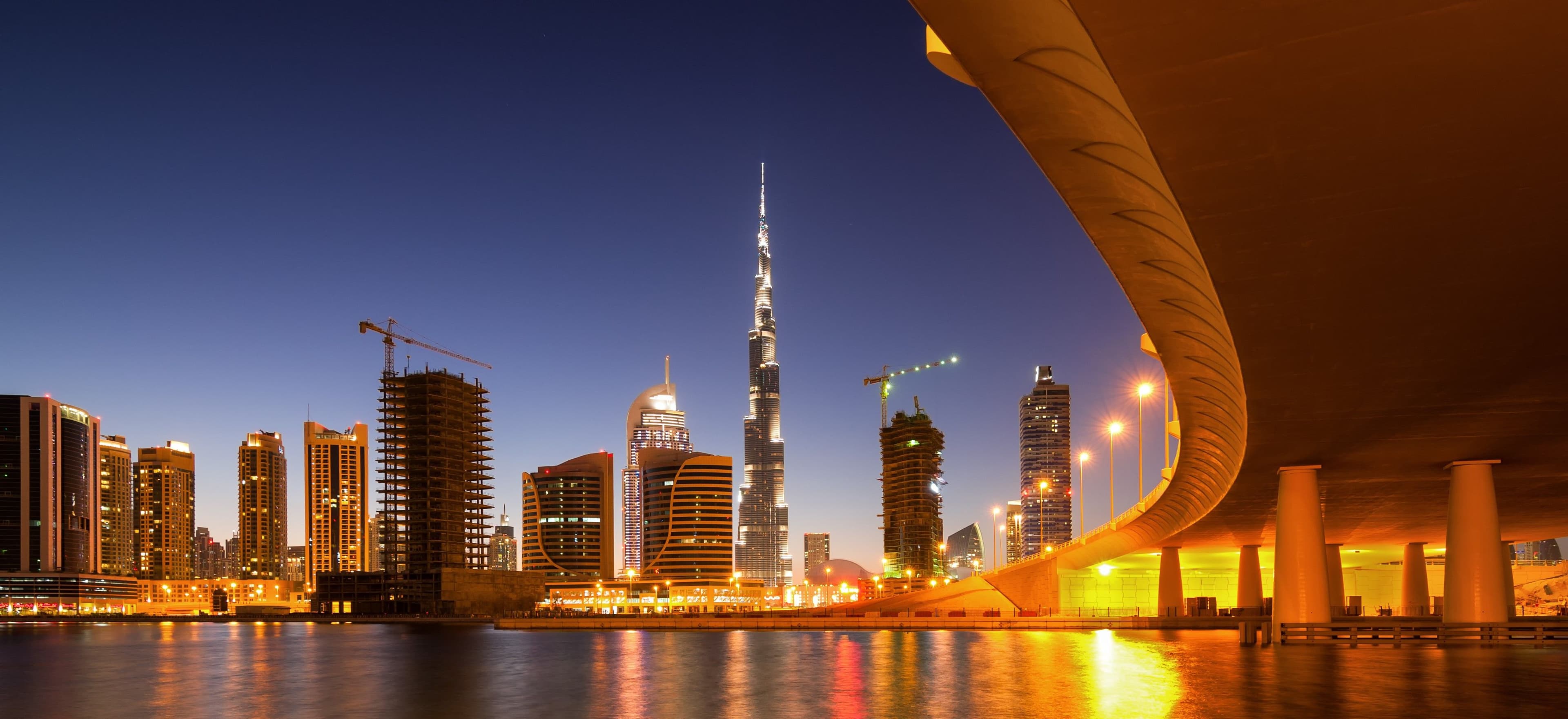 Dubai skyline at night with Burj Khalifa and illuminated bridge reflecting economic strength and urban stability